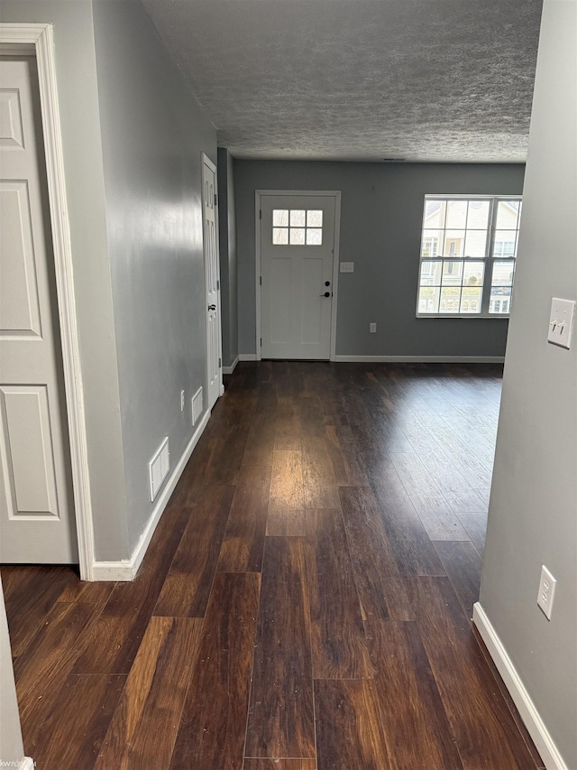 foyer entrance with a textured ceiling and dark hardwood / wood-style flooring