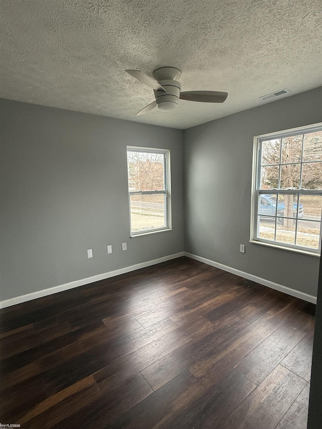 spare room with a textured ceiling, ceiling fan, and dark hardwood / wood-style floors