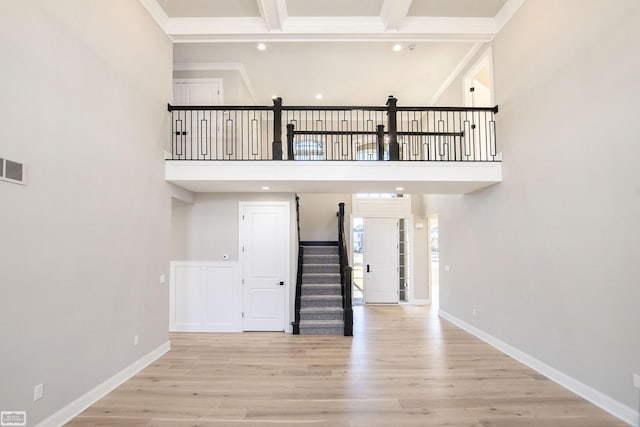 staircase featuring beamed ceiling, wood-type flooring, and a high ceiling