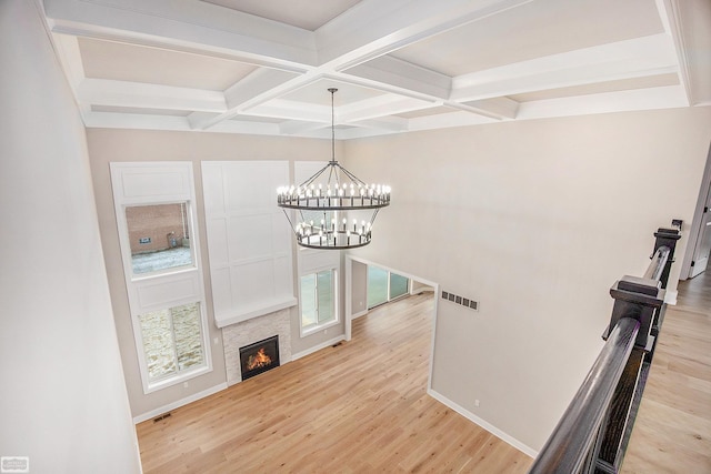 living room with beam ceiling, light hardwood / wood-style flooring, a chandelier, and coffered ceiling