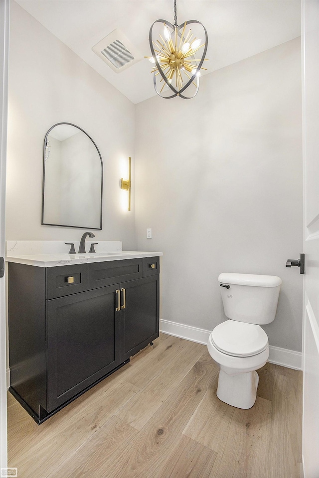 bathroom featuring a chandelier, vanity, hardwood / wood-style flooring, and toilet