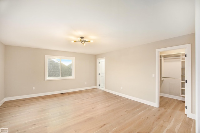 spare room featuring light hardwood / wood-style flooring and an inviting chandelier