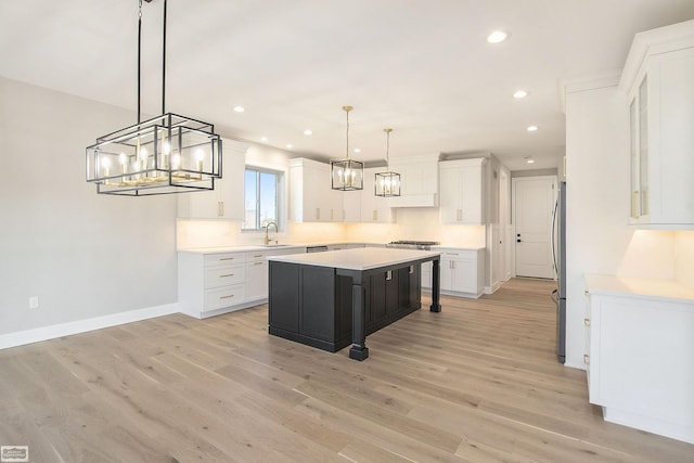 kitchen featuring stainless steel fridge, decorative light fixtures, a center island, light hardwood / wood-style floors, and white cabinetry