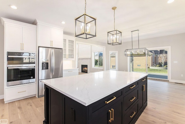 kitchen featuring a center island, hanging light fixtures, light hardwood / wood-style floors, white cabinets, and appliances with stainless steel finishes