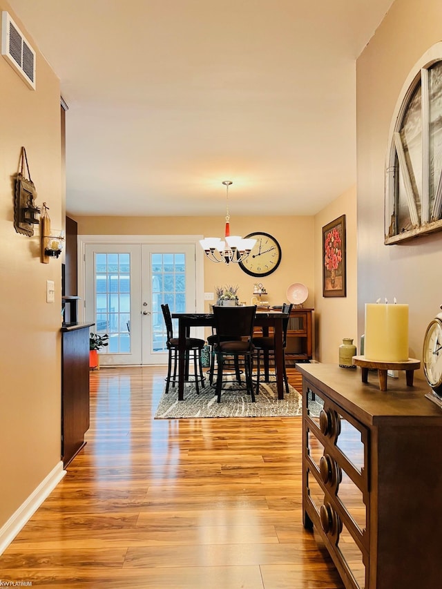 dining area featuring french doors, light hardwood / wood-style flooring, and an inviting chandelier