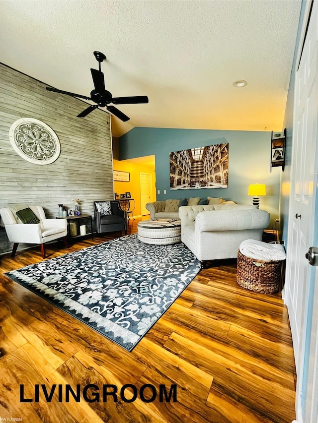 living room with a textured ceiling, ceiling fan, hardwood / wood-style flooring, lofted ceiling, and wood walls