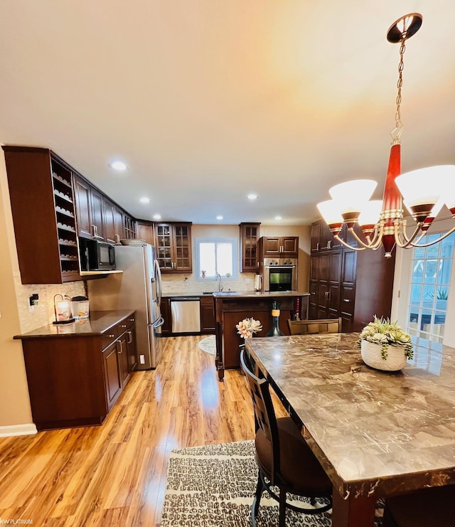 kitchen featuring decorative light fixtures, appliances with stainless steel finishes, tasteful backsplash, a notable chandelier, and dark brown cabinetry