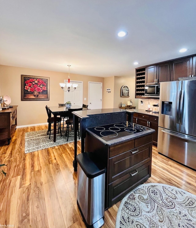 kitchen with a center island, stainless steel refrigerator with ice dispenser, light hardwood / wood-style floors, decorative light fixtures, and electric stovetop