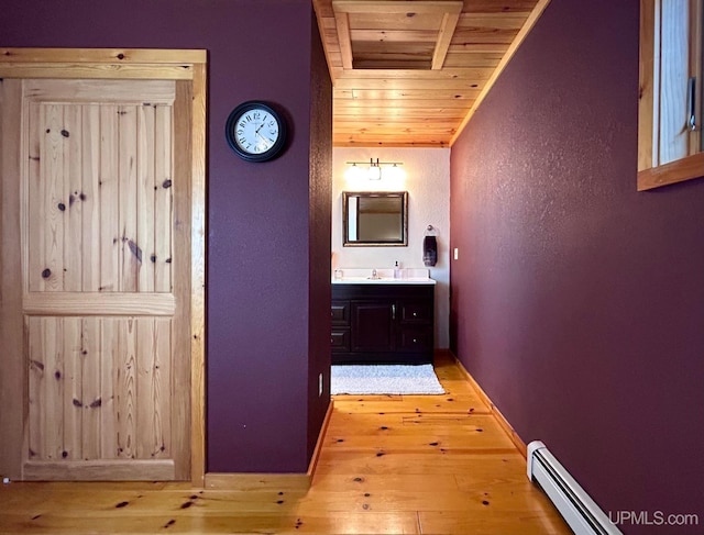 corridor featuring light hardwood / wood-style flooring, wood ceiling, a baseboard radiator, and sink