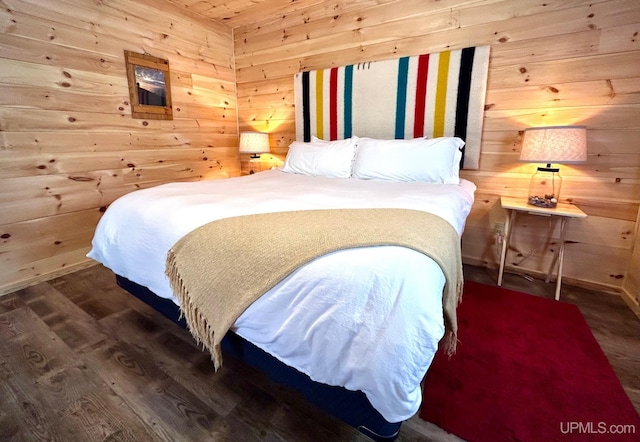 bedroom with wood walls and dark wood-type flooring