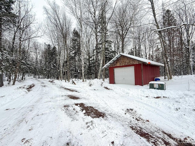 snowy yard featuring an outbuilding and a garage