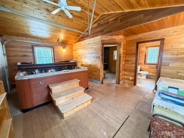 interior space with lofted ceiling, wooden ceiling, ceiling fan, and wooden walls