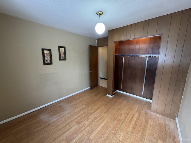 unfurnished bedroom featuring light hardwood / wood-style floors and wood walls