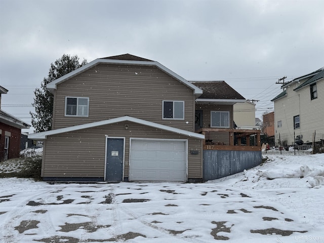 snow covered rear of property featuring a garage