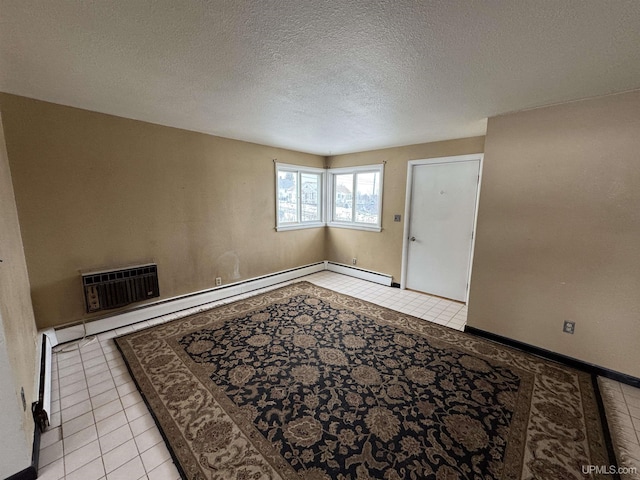 tiled spare room featuring a textured ceiling and a baseboard heating unit