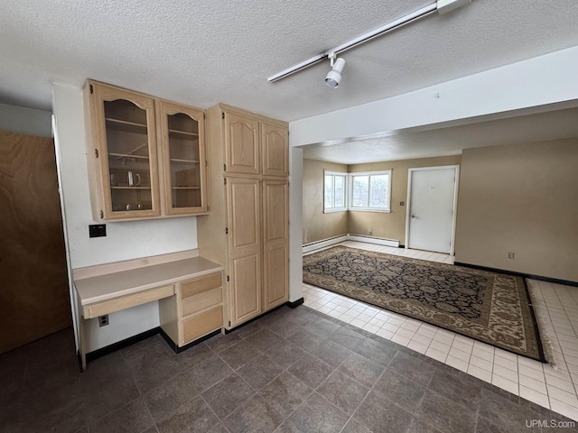 kitchen with a textured ceiling, light brown cabinetry, and track lighting