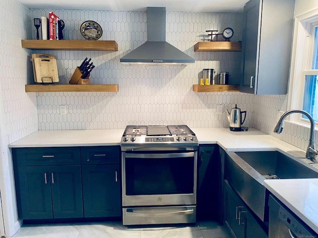 kitchen featuring blue cabinetry, wall chimney exhaust hood, sink, and stainless steel stove