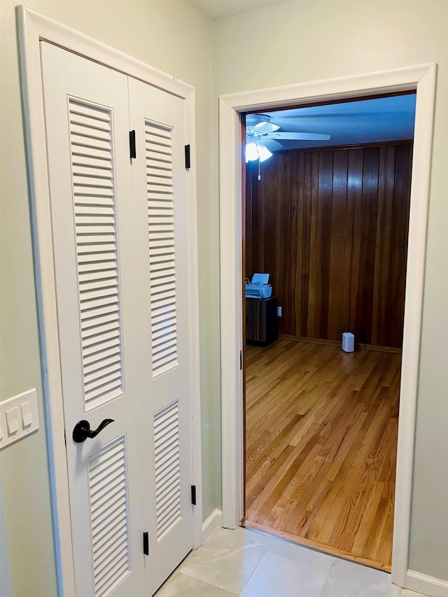 hallway with wood walls and light tile patterned floors