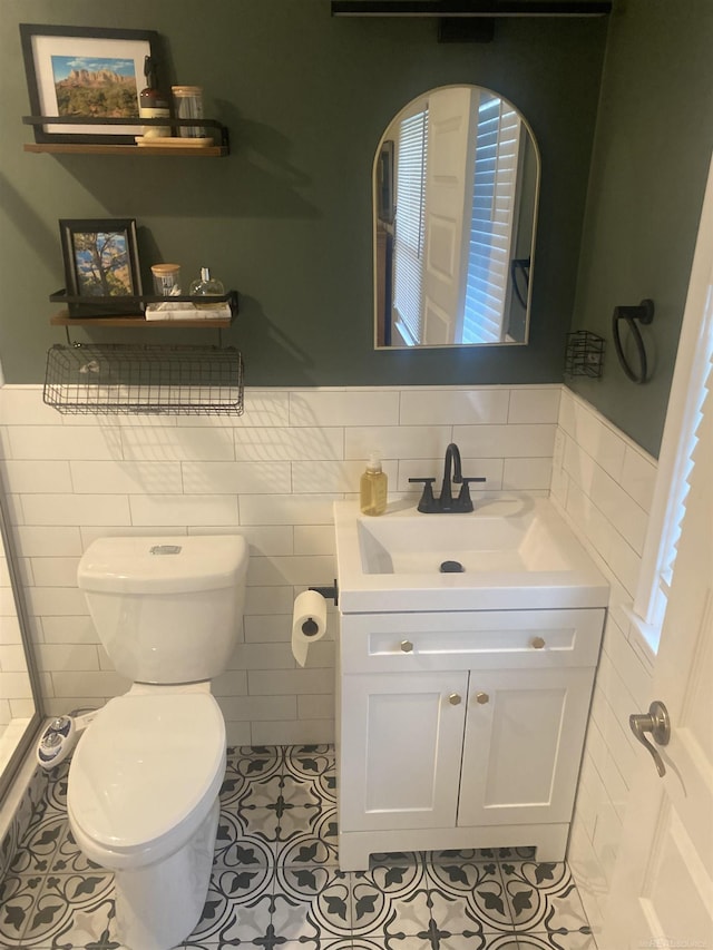 bathroom with tile patterned floors, vanity, tile walls, and toilet