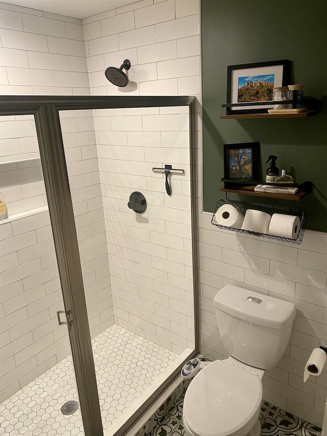 bathroom with tile patterned floors, toilet, tile walls, and walk in shower