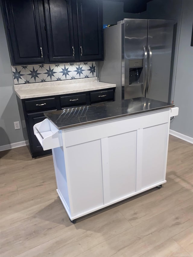 kitchen with light hardwood / wood-style floors, stainless steel refrigerator with ice dispenser, and tasteful backsplash