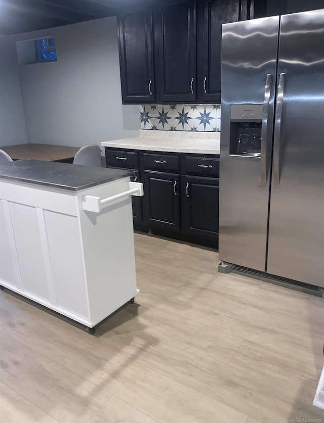 kitchen with stainless steel fridge, tasteful backsplash, and light hardwood / wood-style flooring