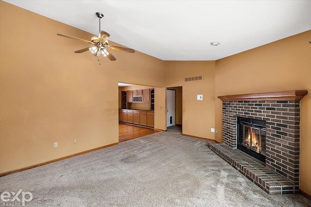 unfurnished living room featuring a fireplace, carpet, vaulted ceiling, and ceiling fan