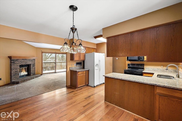 kitchen with an inviting chandelier, black appliances, sink, decorative light fixtures, and kitchen peninsula