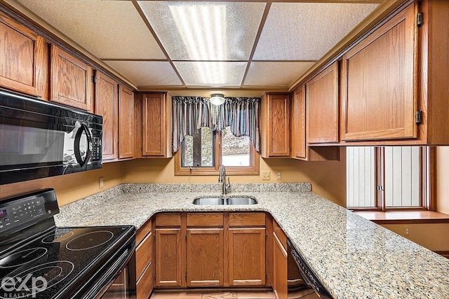 kitchen with black appliances, light stone countertops, and sink