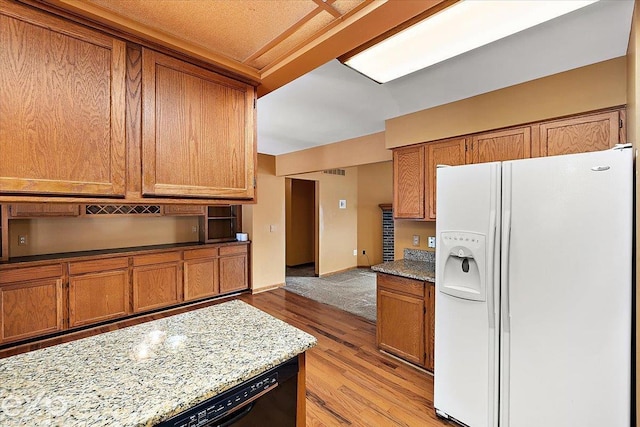 kitchen featuring light stone countertops, black dishwasher, white refrigerator with ice dispenser, and light wood-type flooring