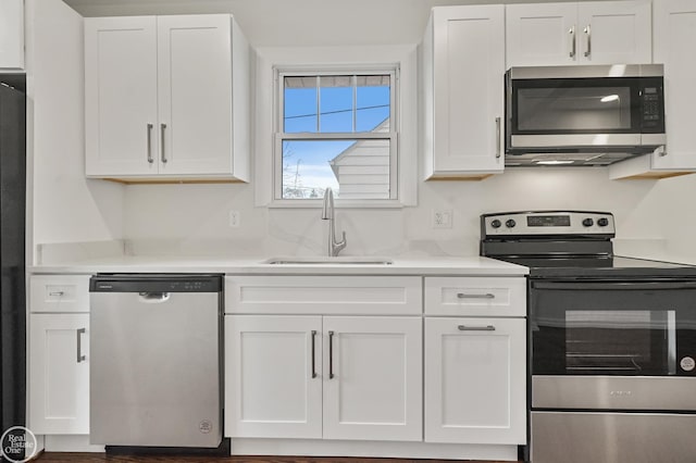 kitchen with white cabinetry, sink, light stone countertops, and appliances with stainless steel finishes