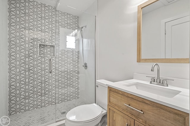 bathroom featuring tiled shower, vanity, and toilet