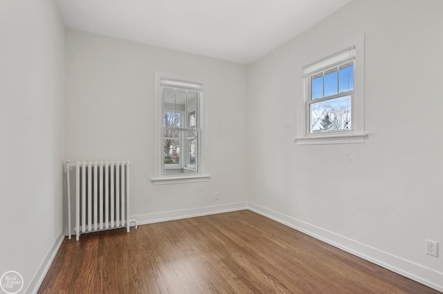 spare room featuring radiator heating unit and hardwood / wood-style floors