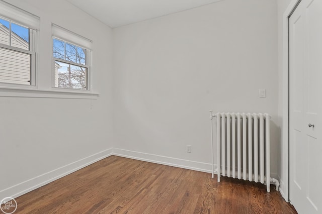 spare room with dark hardwood / wood-style flooring and radiator