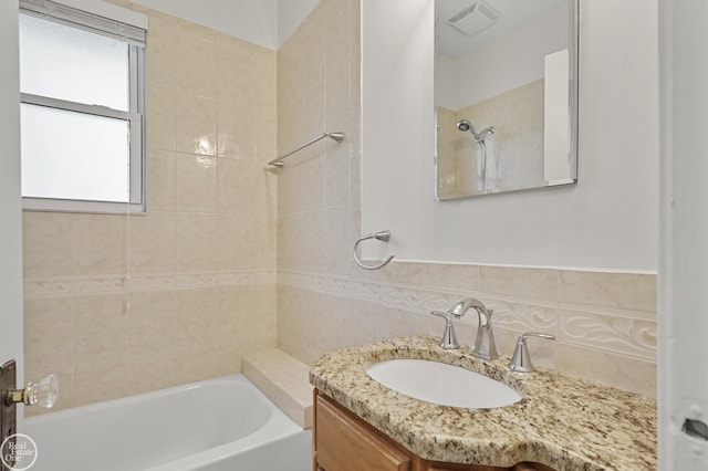 bathroom with backsplash, vanity, and tiled shower / bath combo