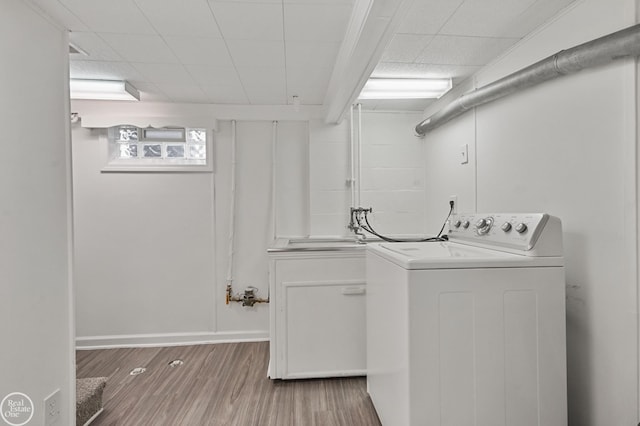 clothes washing area with washer / clothes dryer, cabinets, and hardwood / wood-style flooring