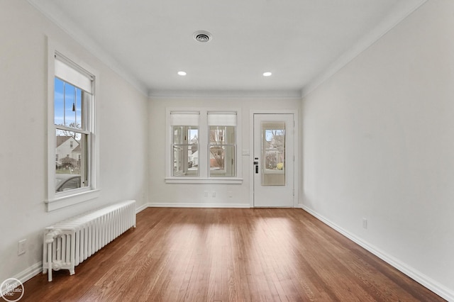 spare room with radiator, crown molding, plenty of natural light, and hardwood / wood-style floors