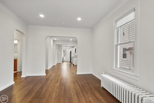 hallway featuring dark wood-type flooring, radiator, and crown molding