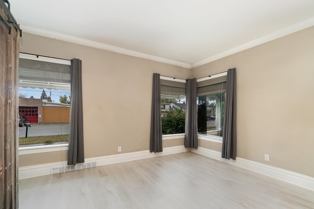 empty room featuring light wood-type flooring and ornamental molding