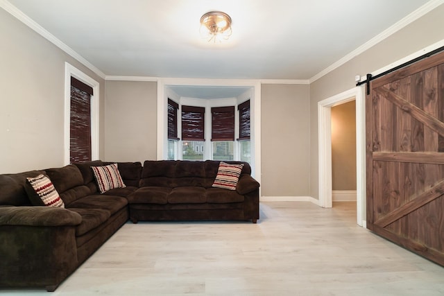 living room with a barn door, light wood-type flooring, and ornamental molding