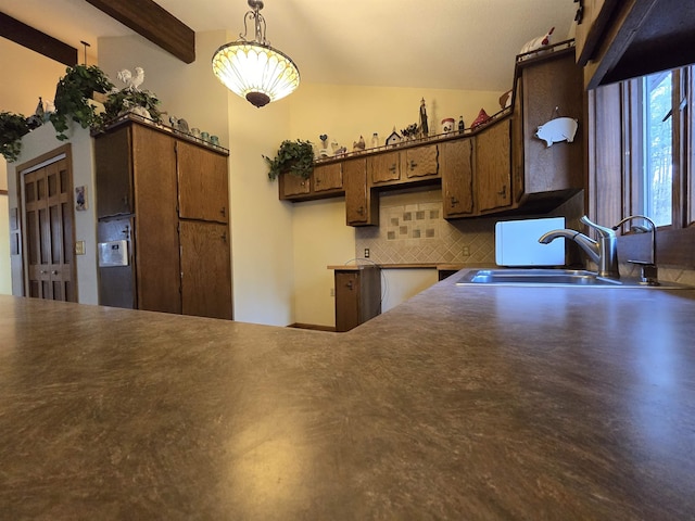 kitchen with decorative backsplash, kitchen peninsula, sink, beamed ceiling, and hanging light fixtures