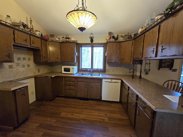 kitchen with white appliances, dark wood-type flooring, sink, hanging light fixtures, and vaulted ceiling