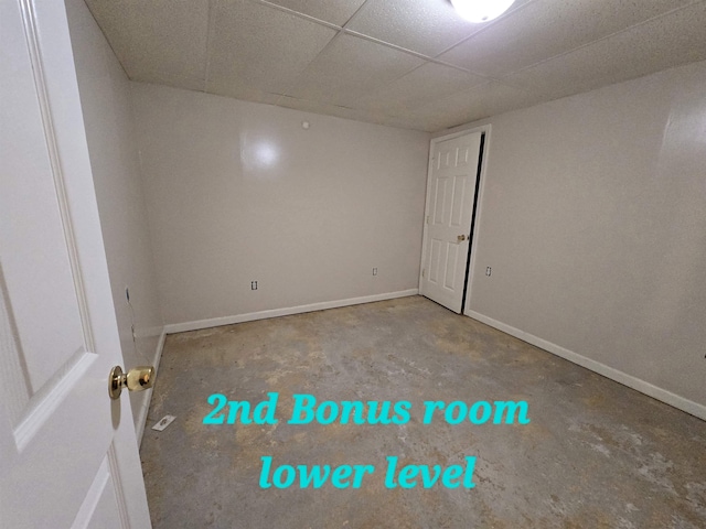 unfurnished room with a drop ceiling and concrete floors