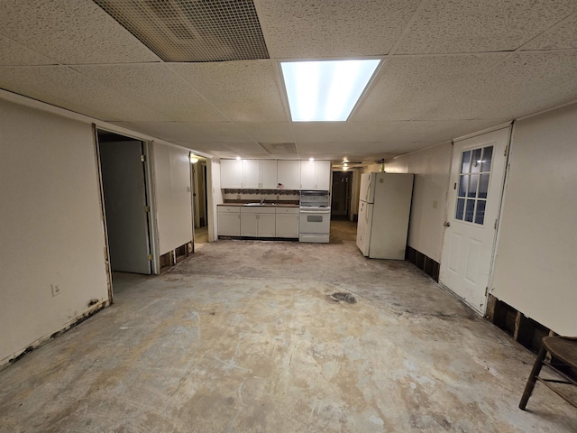 basement with a drop ceiling and white fridge