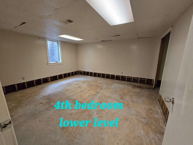 empty room with a paneled ceiling and concrete floors