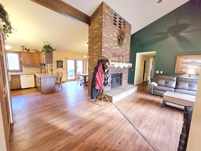 living room with high vaulted ceiling, ceiling fan, light wood-type flooring, a fireplace, and beamed ceiling