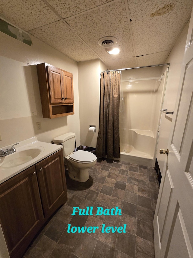 bathroom with a paneled ceiling, a shower with curtain, vanity, and toilet