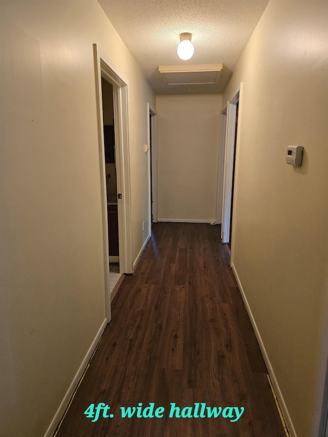 corridor featuring a textured ceiling and dark wood-type flooring