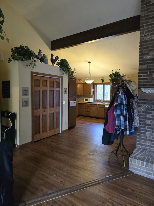 interior space with lofted ceiling with beams, sink, hanging light fixtures, and dark wood-type flooring