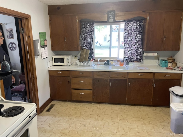 kitchen with dark brown cabinetry, white appliances, and sink